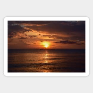 Mesmerizing vertical shot of the sun setting behind the clouds over the calm ocean Sticker